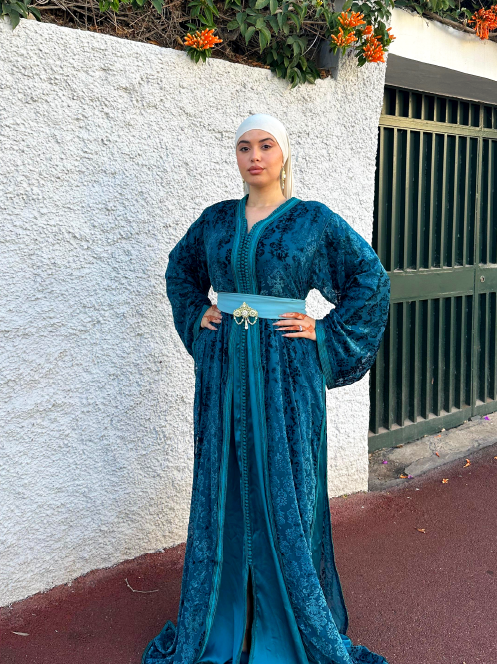 caftan turquoise en tissu texturé avec une ceinture assortie ornée d’un bijou doré