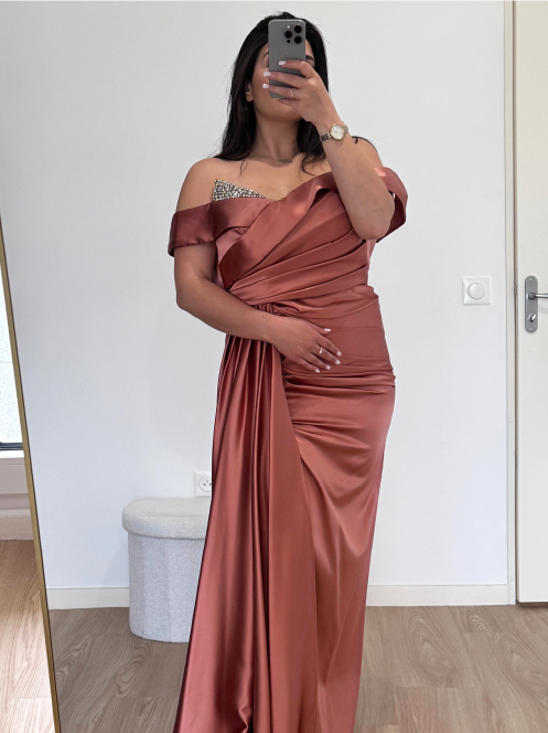 Robe de soirée terracotta en satin doux, drapée avec élégance, dévoilant les épaules pour un look chic et moderne.